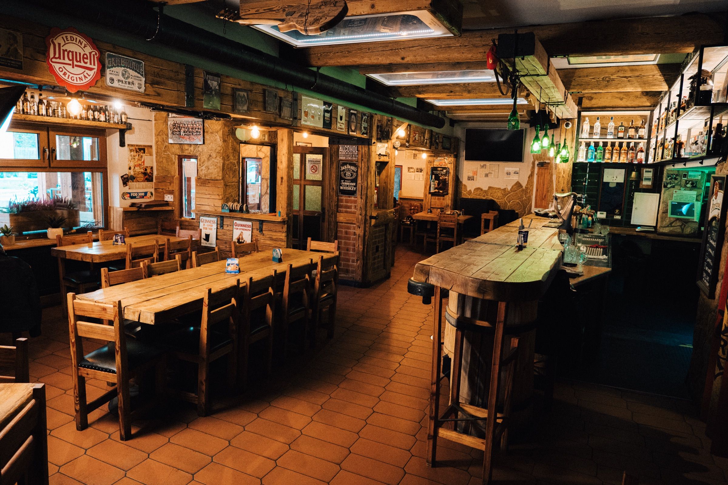 Interiér pubu — dřevěné stoly, bar a zesilovače Marshall
