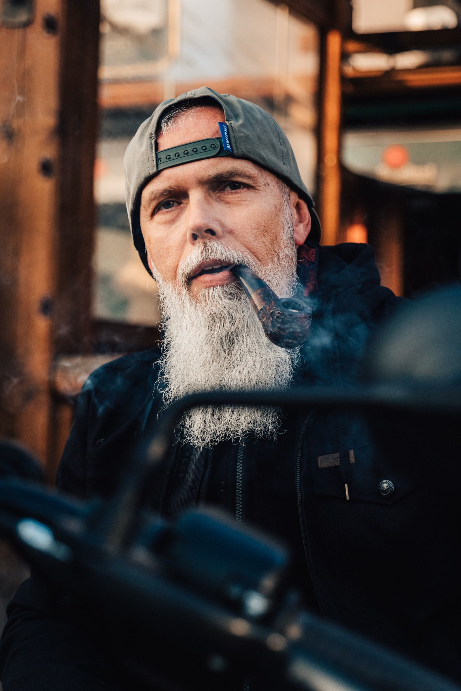 Motorkář s bílým plnovousem a dýmkou před KNAKem