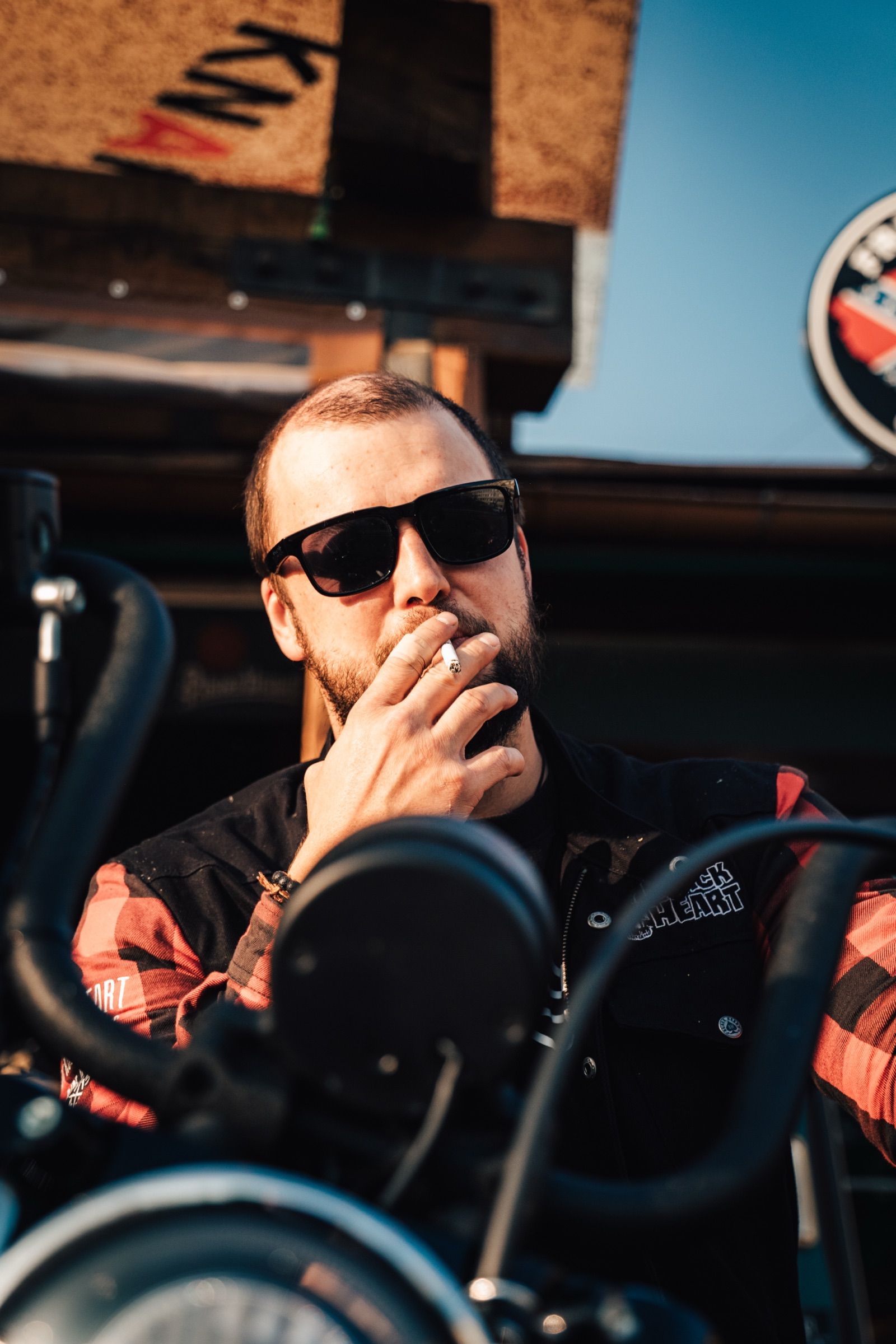 Motorkář v brýlích na motorce před terasou