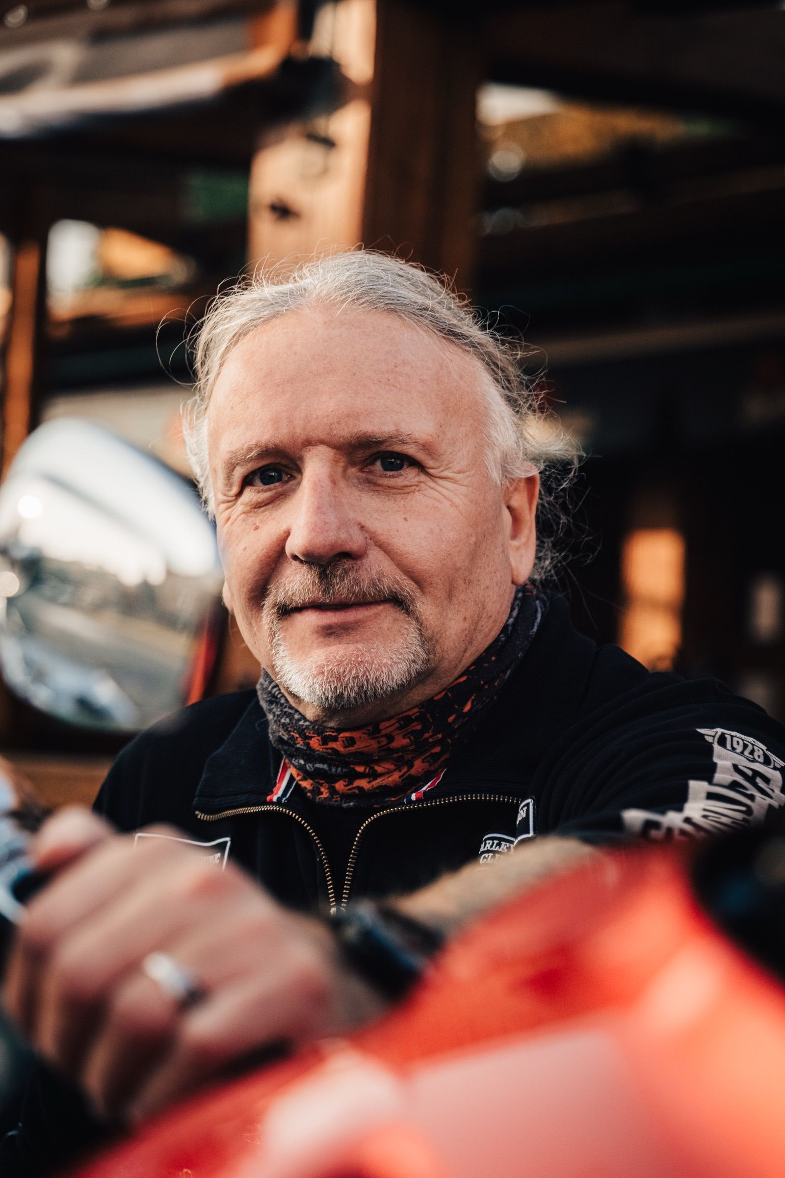 Šedovlasý motorkář s rukou na řídítkách
