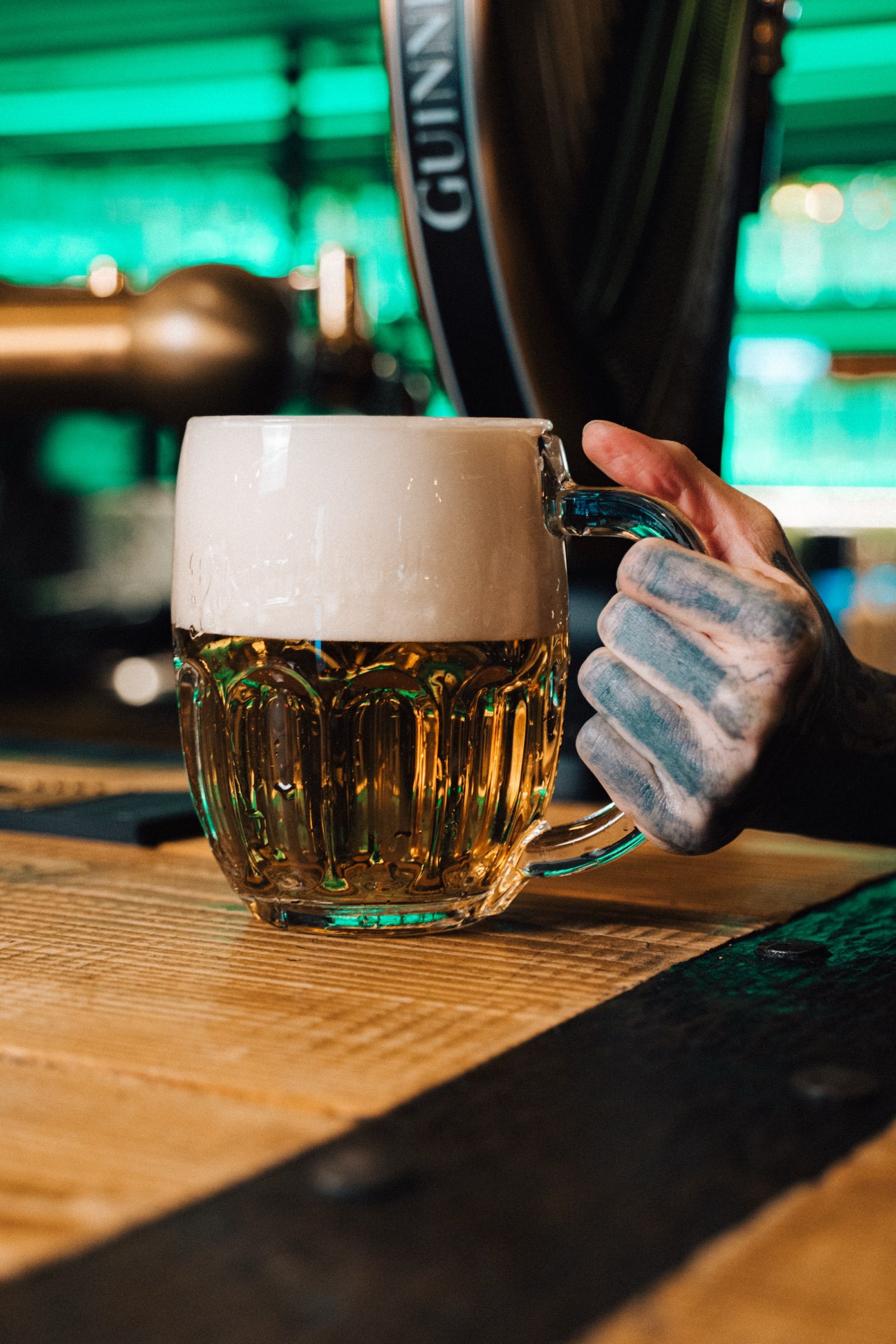 Půllitr Pilsner Urquell na baru, v pozadí harfa Guinness